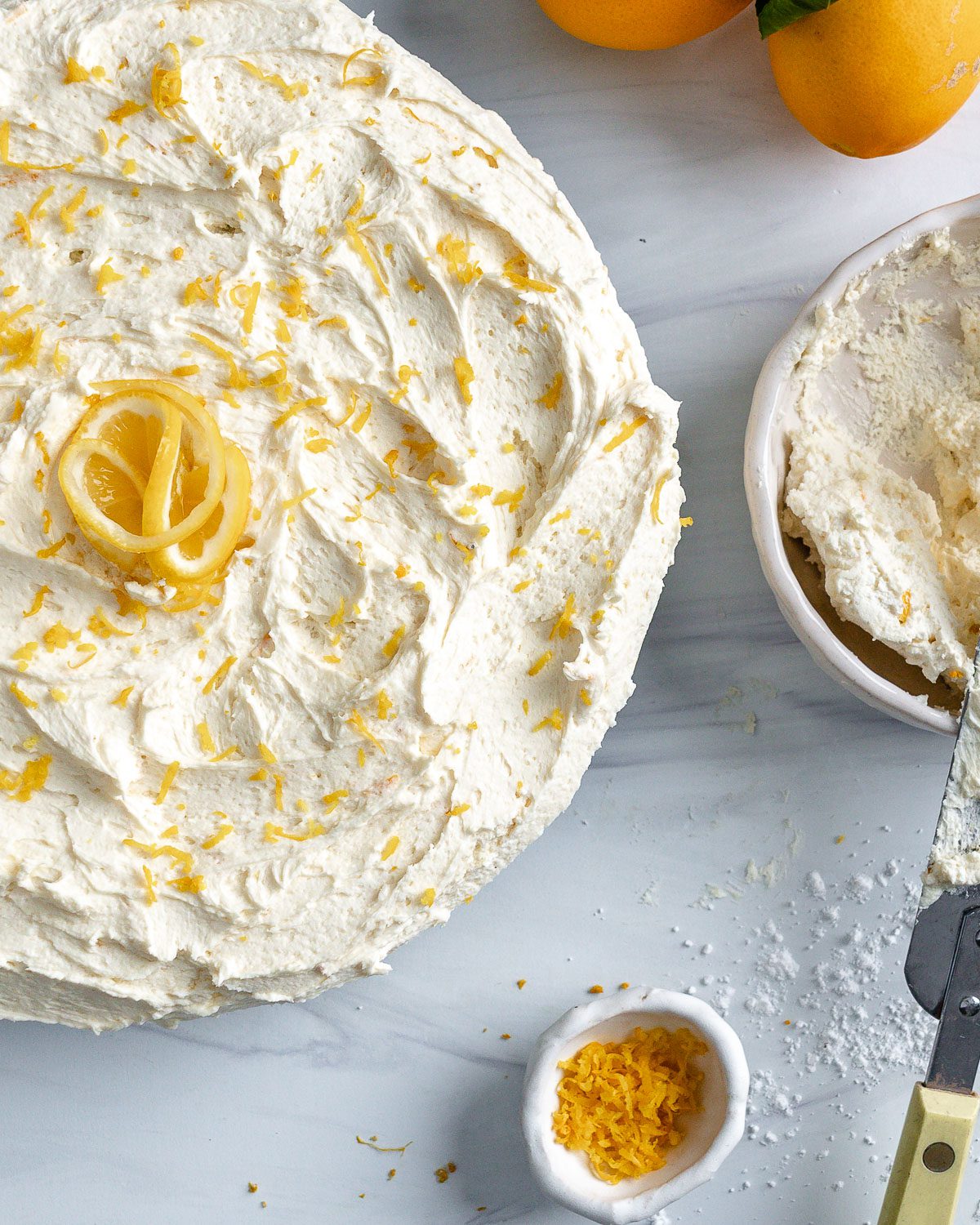 completed lemon cake with ingredients in individual bowls against a white background