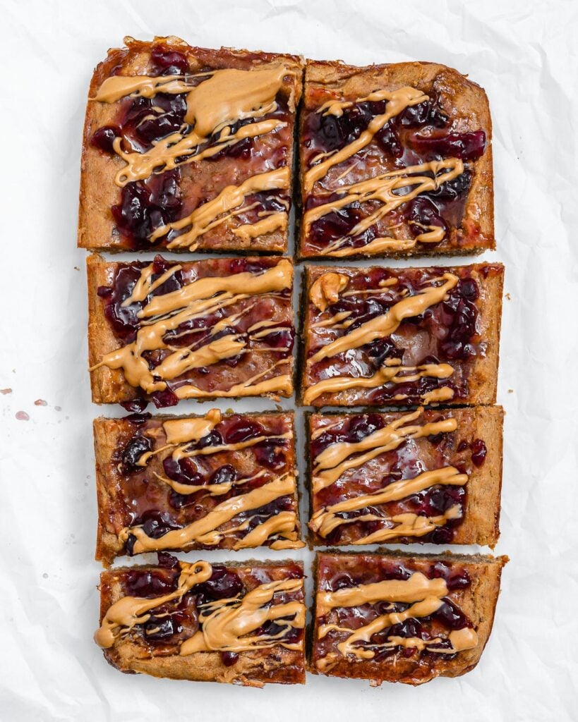 Completed and sliced Peanut Butter and Jelly Blondie Bars on a white surface.