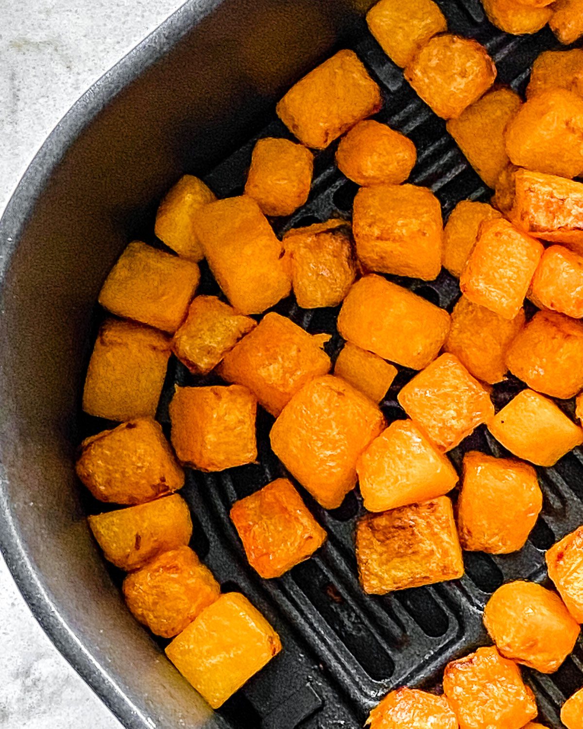 Process shot showing post-cooked Simple Air Fryer Butternut Squash laid out in an air fryer basket.