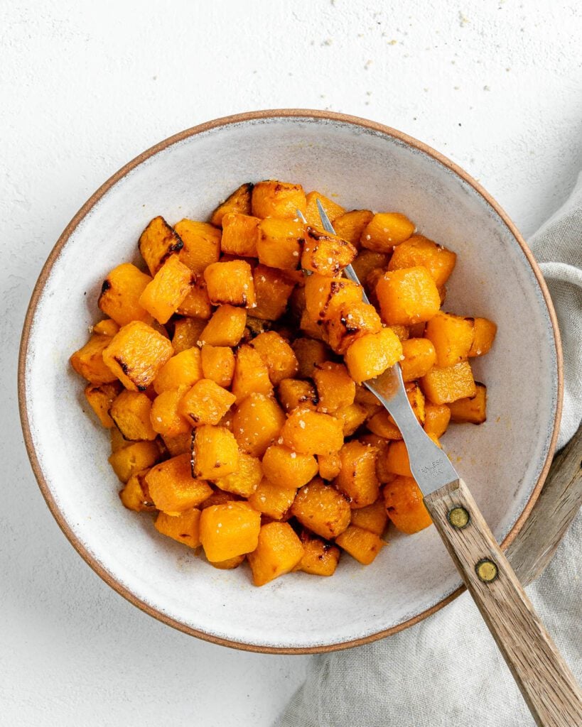 Completed Simple Air Fryer Butternut Squash in a white bowl with a utensil in the bowl.