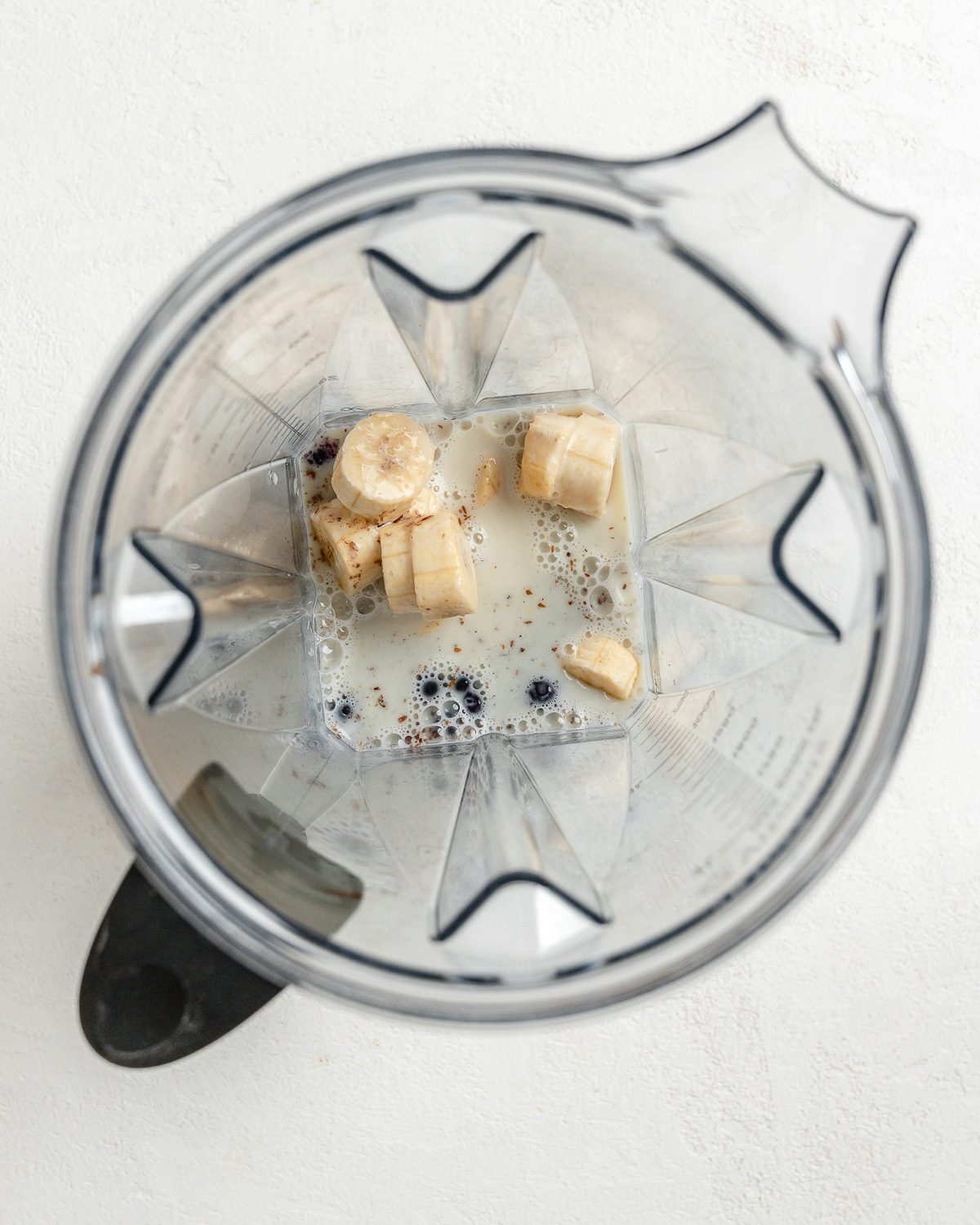 ingredients for blueberry banana smoothie in blender against a white background