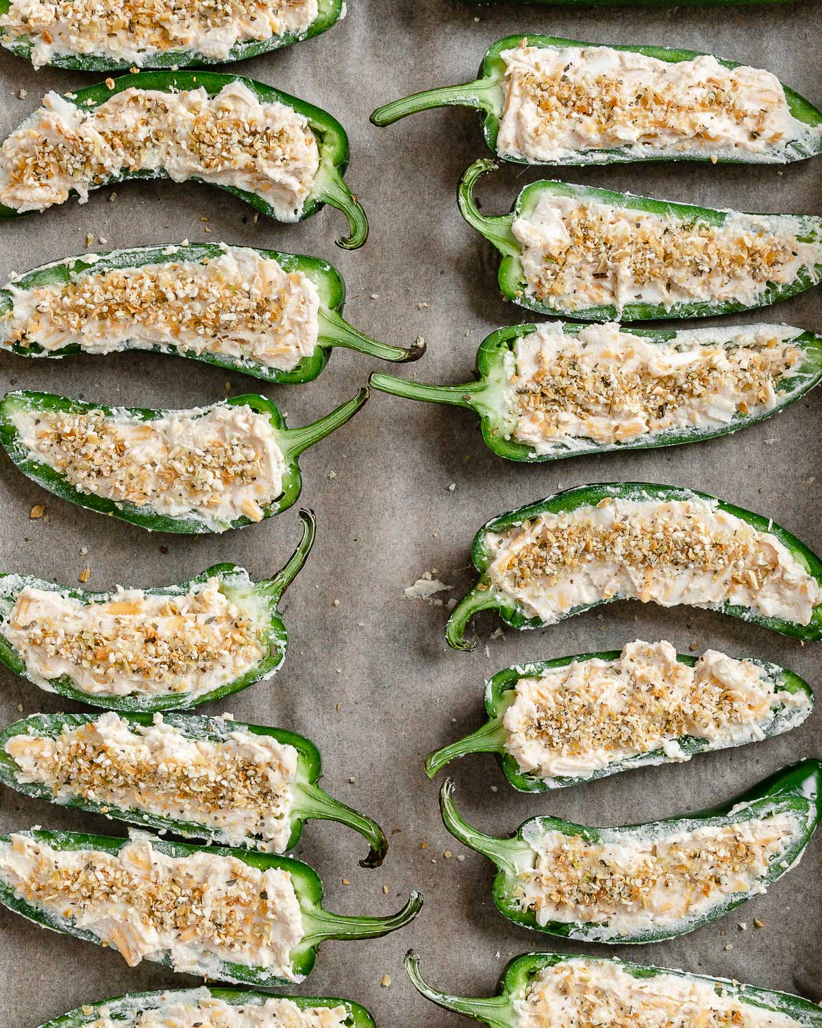 pre baked jalapeno poppers spread out on a baking tray