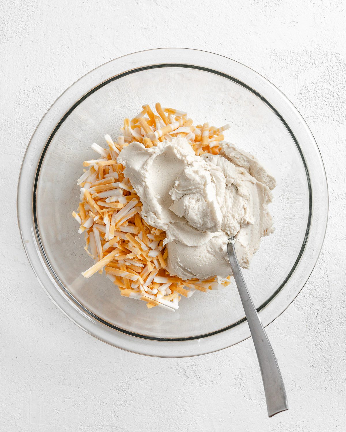 process of mixing flour mixture into clear glass bowl against white background