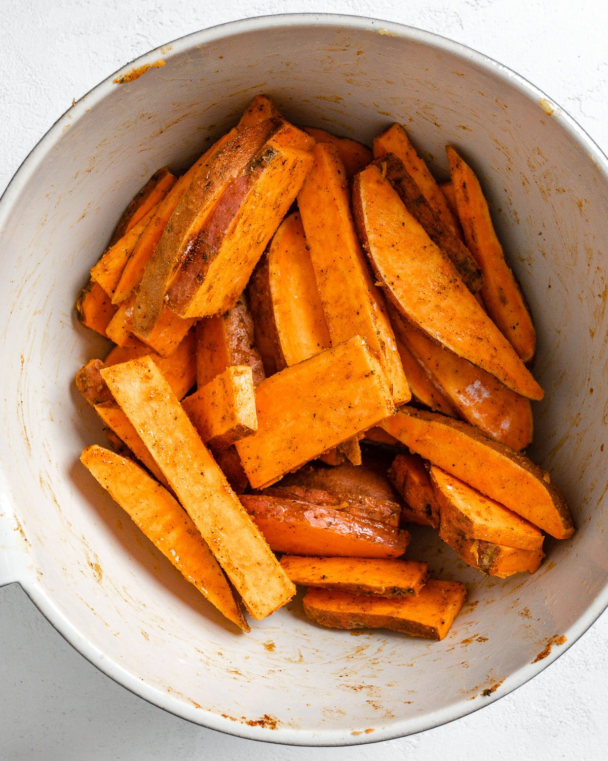 raw sweet potato wedges in a white bowl
