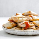 completed Air Fryer Pizza Rolls in a white speckled plate against a white background