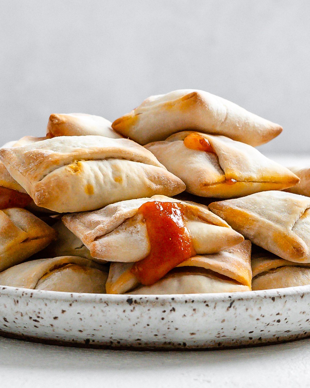 completed Air Fryer Pizza Rolls in a white speckled plate against a white background