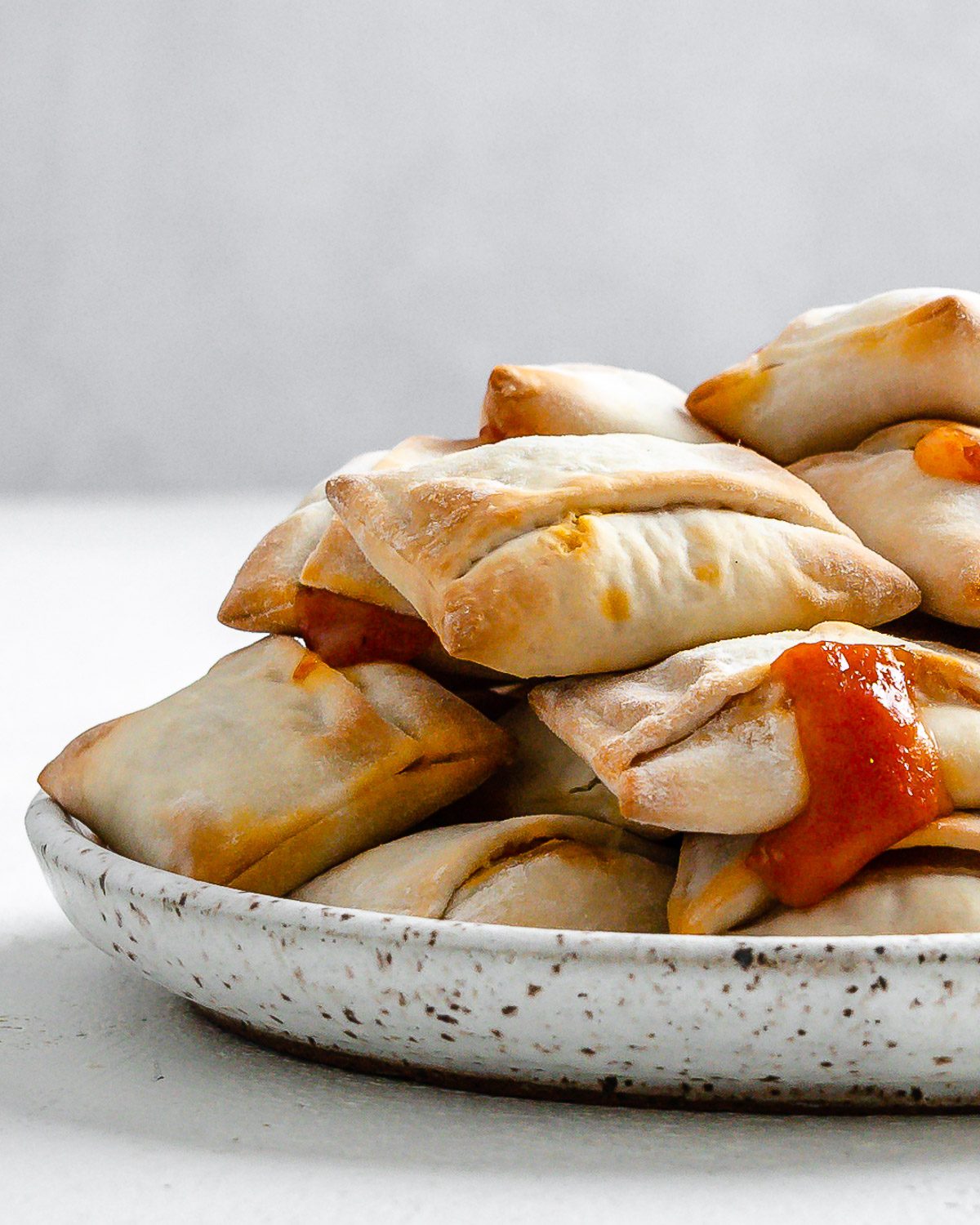 completed Air Fryer Pizza Rolls in a white speckled plate against a white background
