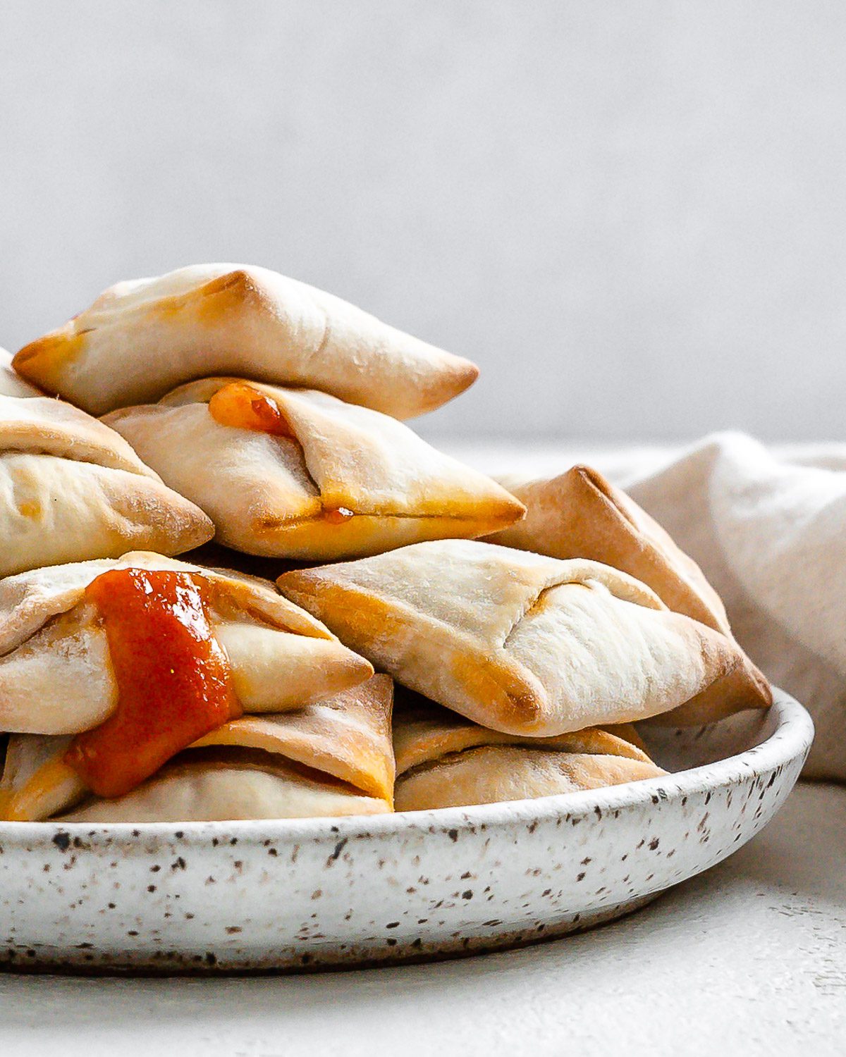 completed Air Fryer Pizza Rolls in a white speckled plate against a white background