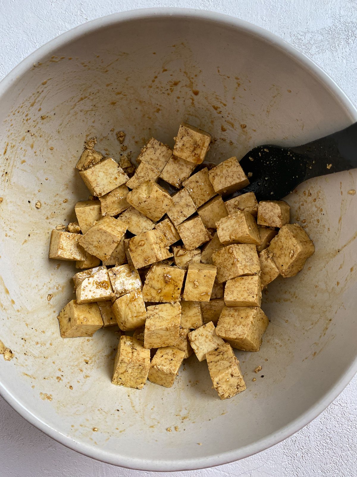 Post mixing of soy sauce and oil in a white bowl.