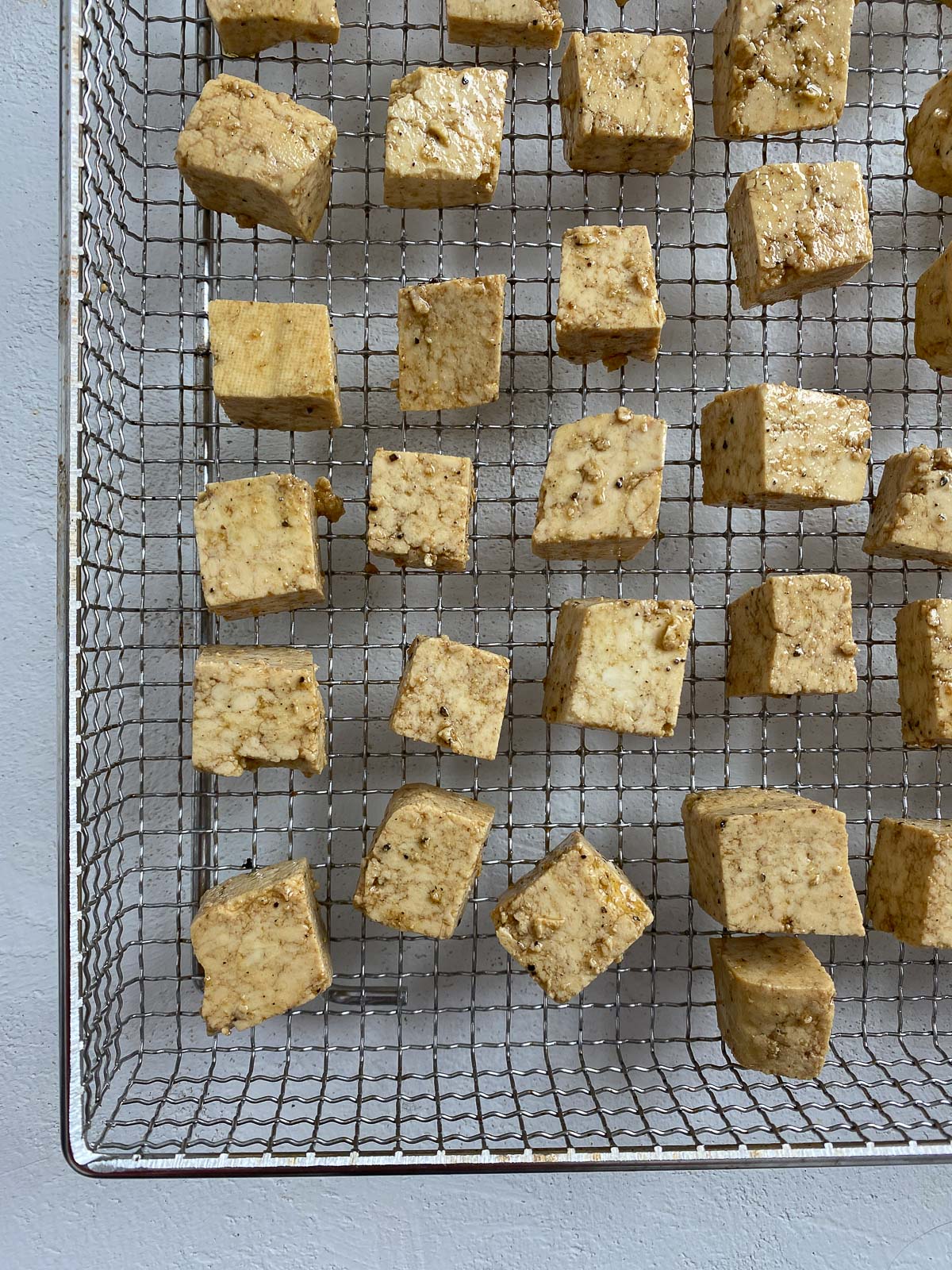 Precooked tofu on an air fryer tray.