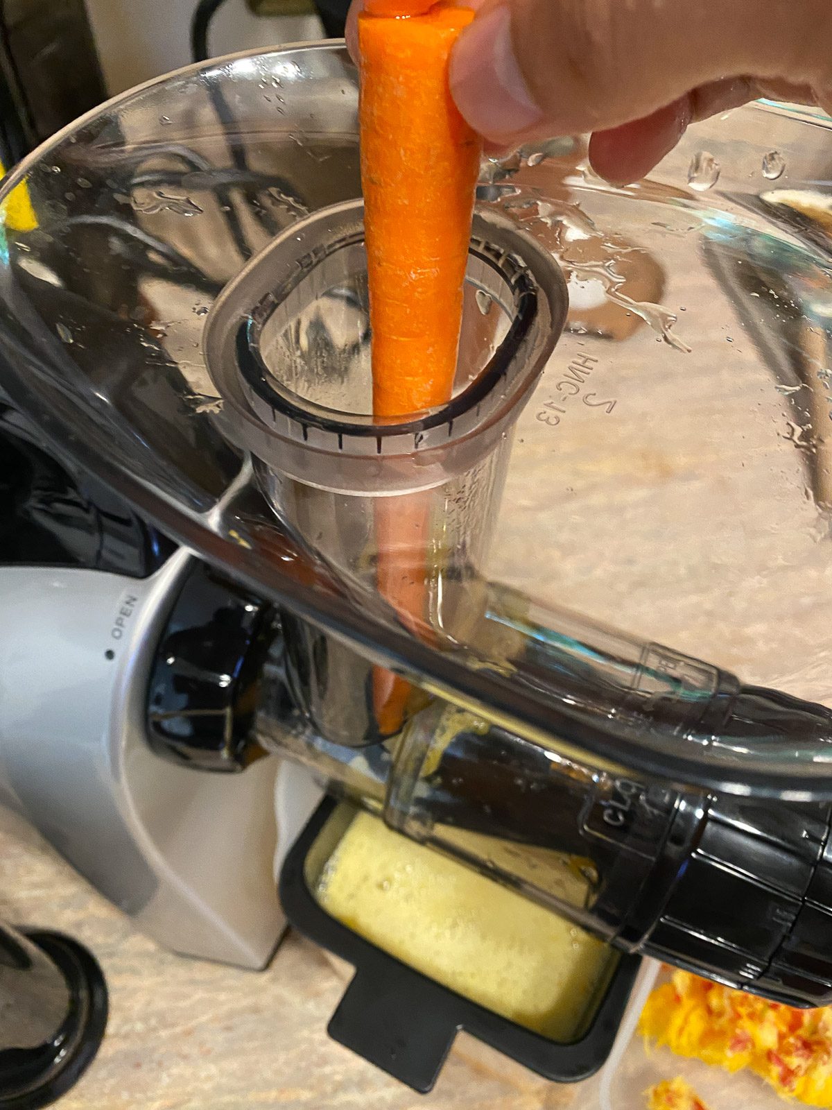 Process shot of adding carrot to juicer.