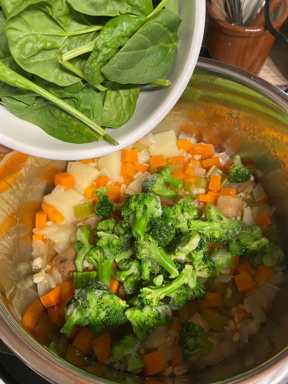 process shot of spinach being added to instant pot