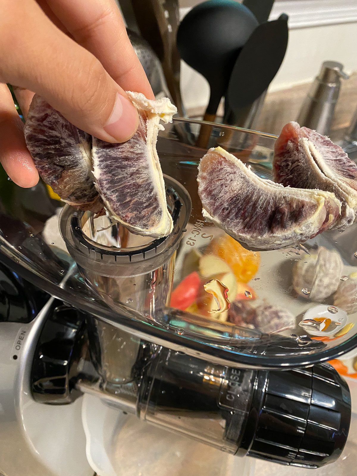 process of putting orange into a juicer