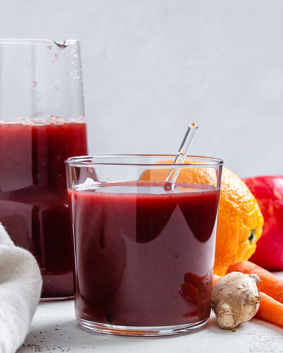 completed Immunity Boosting Juice in two glasses with ingredients in the background