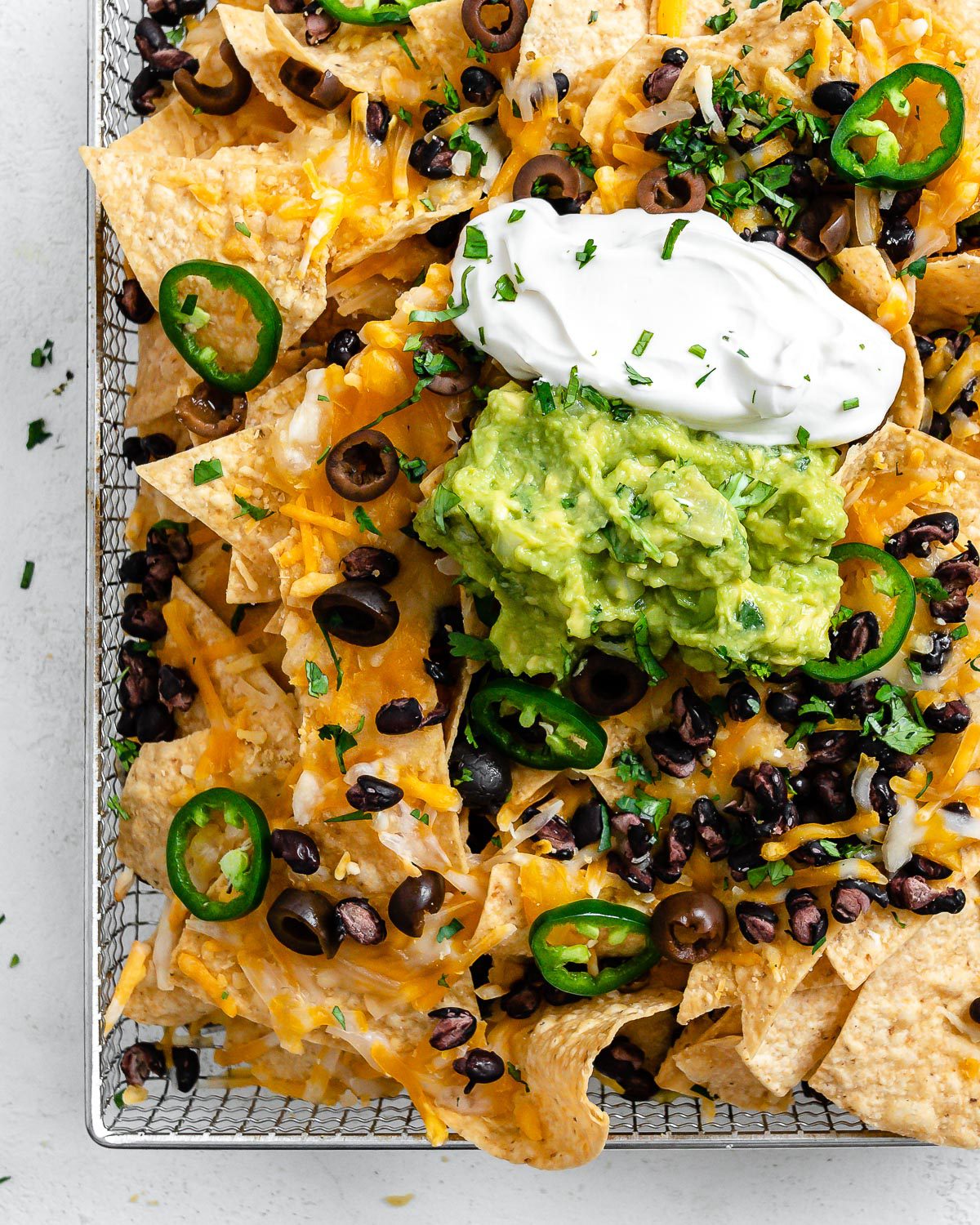 completed Vegan Air Fryer Nachos on air fryer tray against white surface