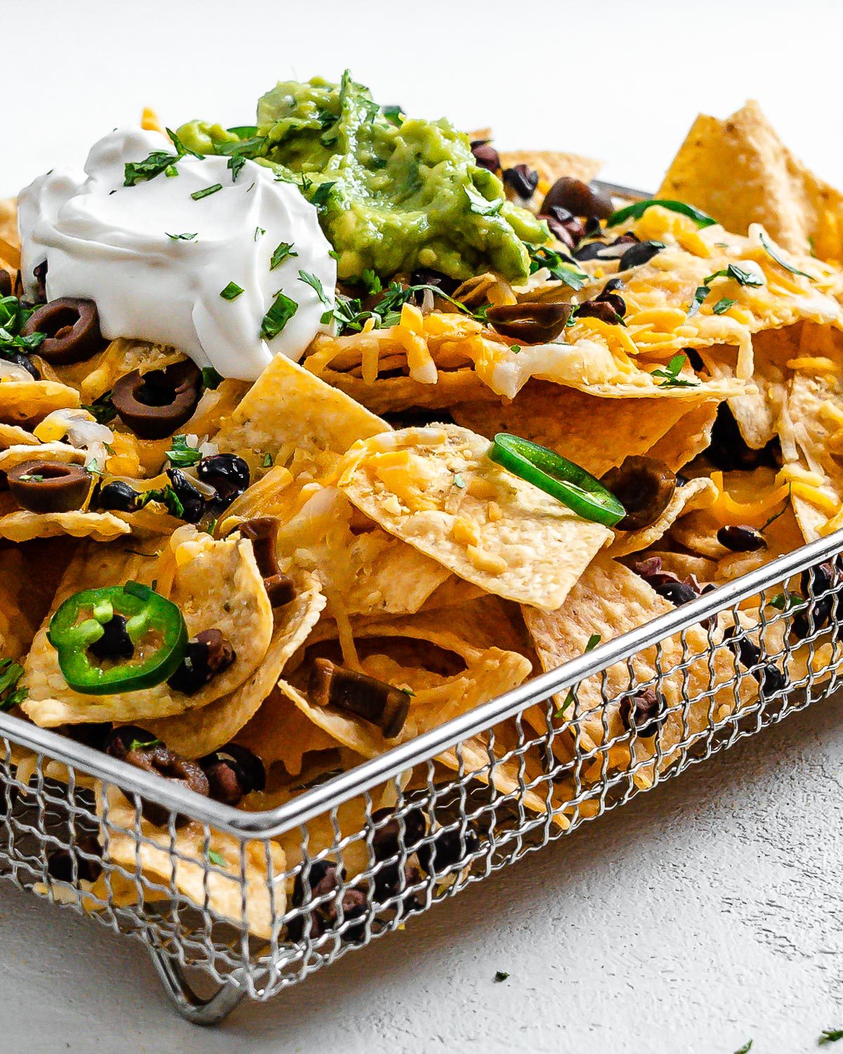completed Vegan Air Fryer Nachos on air fryer tray against white surface