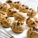 several completed Vegan Raisin Oatmeal Cookies spread out on a white surface