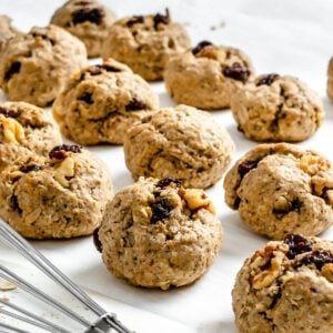 several completed Vegan Raisin Oatmeal Cookies spread out on a white surface