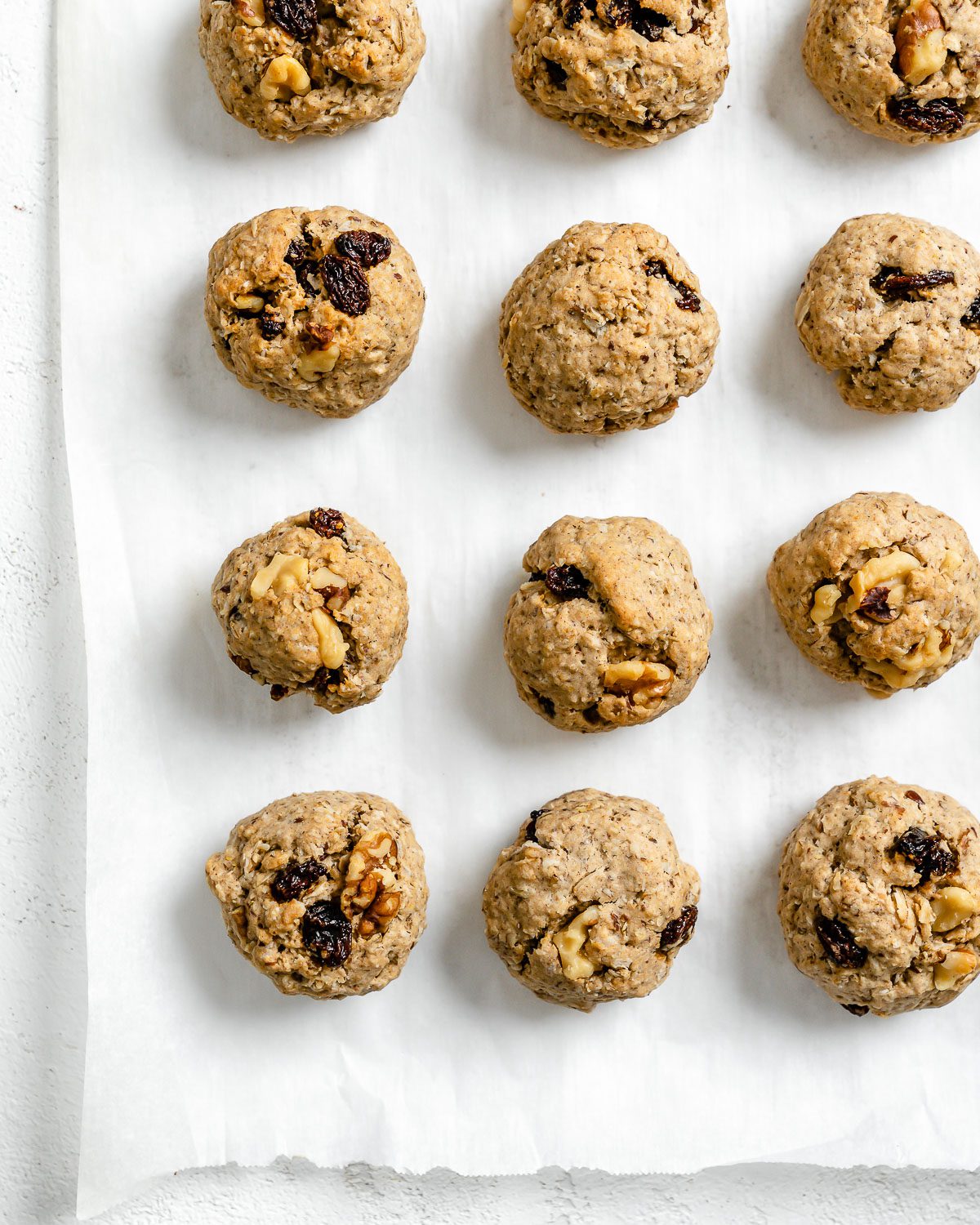 several completed Vegan Raisin Oatmeal Cookies spread out on a white surface