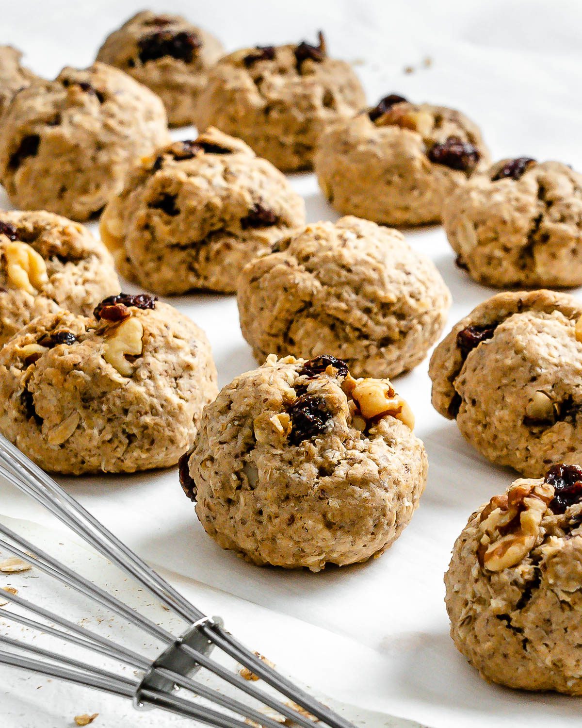 several completed Vegan Raisin Oatmeal Cookies spread out on a white surface