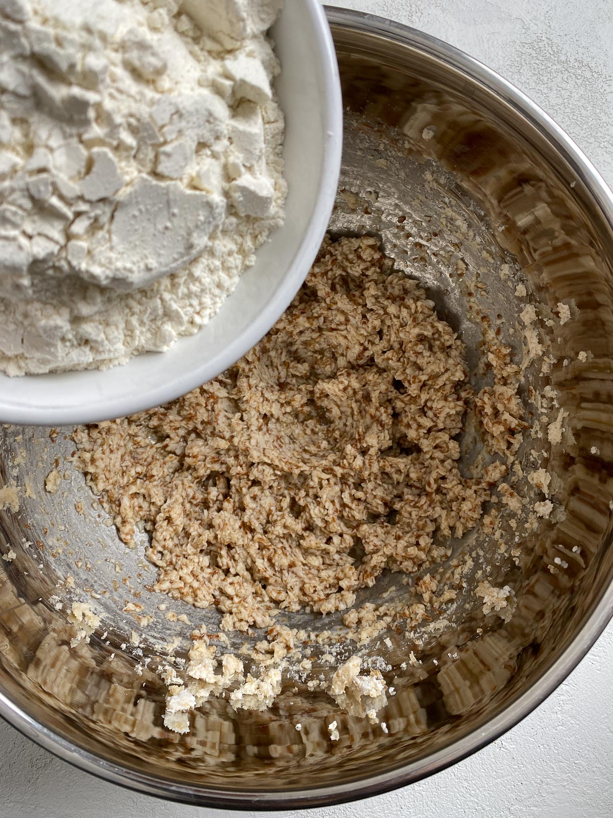process of adding dry ingredients to mixing bowl