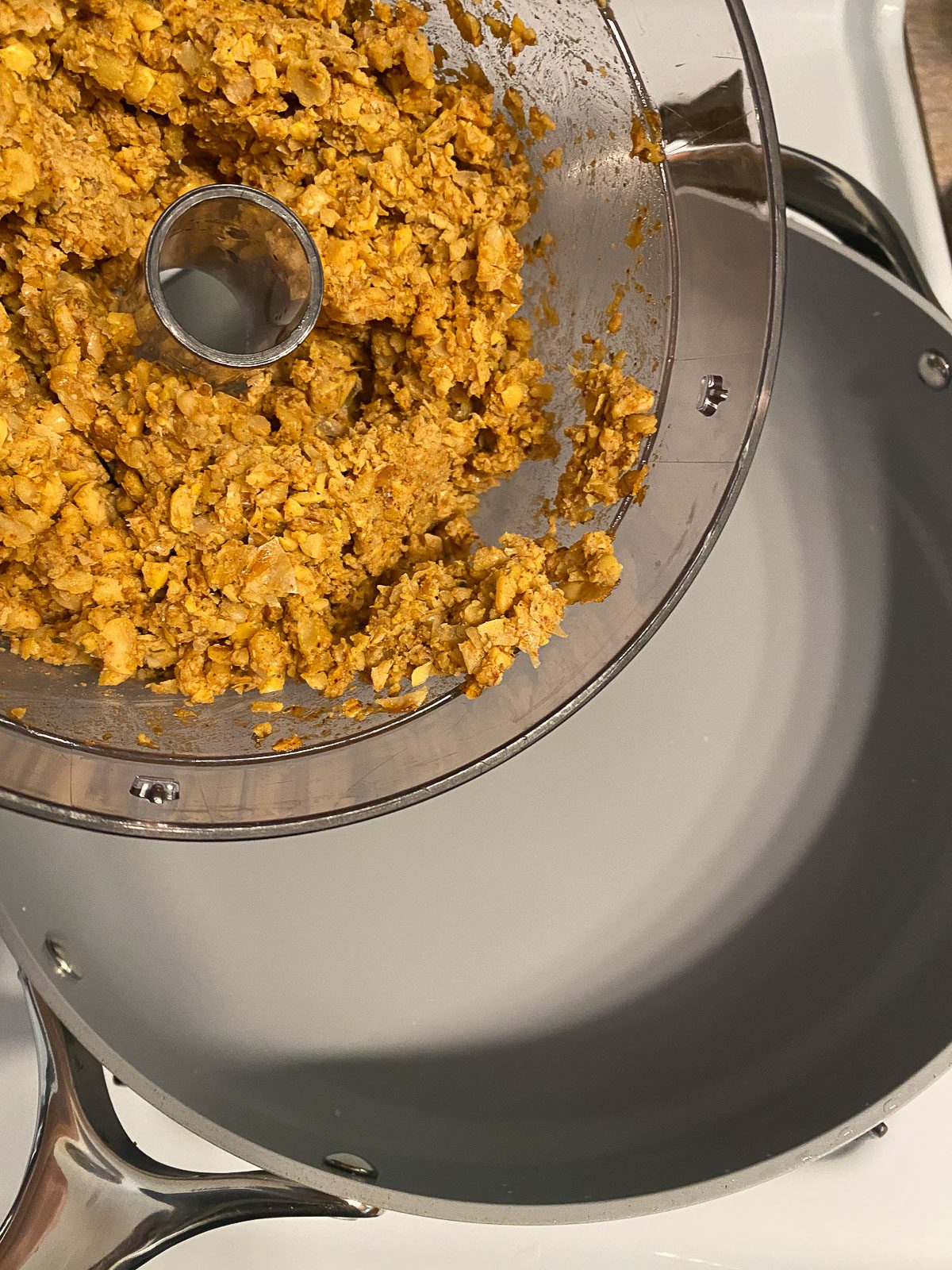 process shot of pouring ingredients from food processor to pan