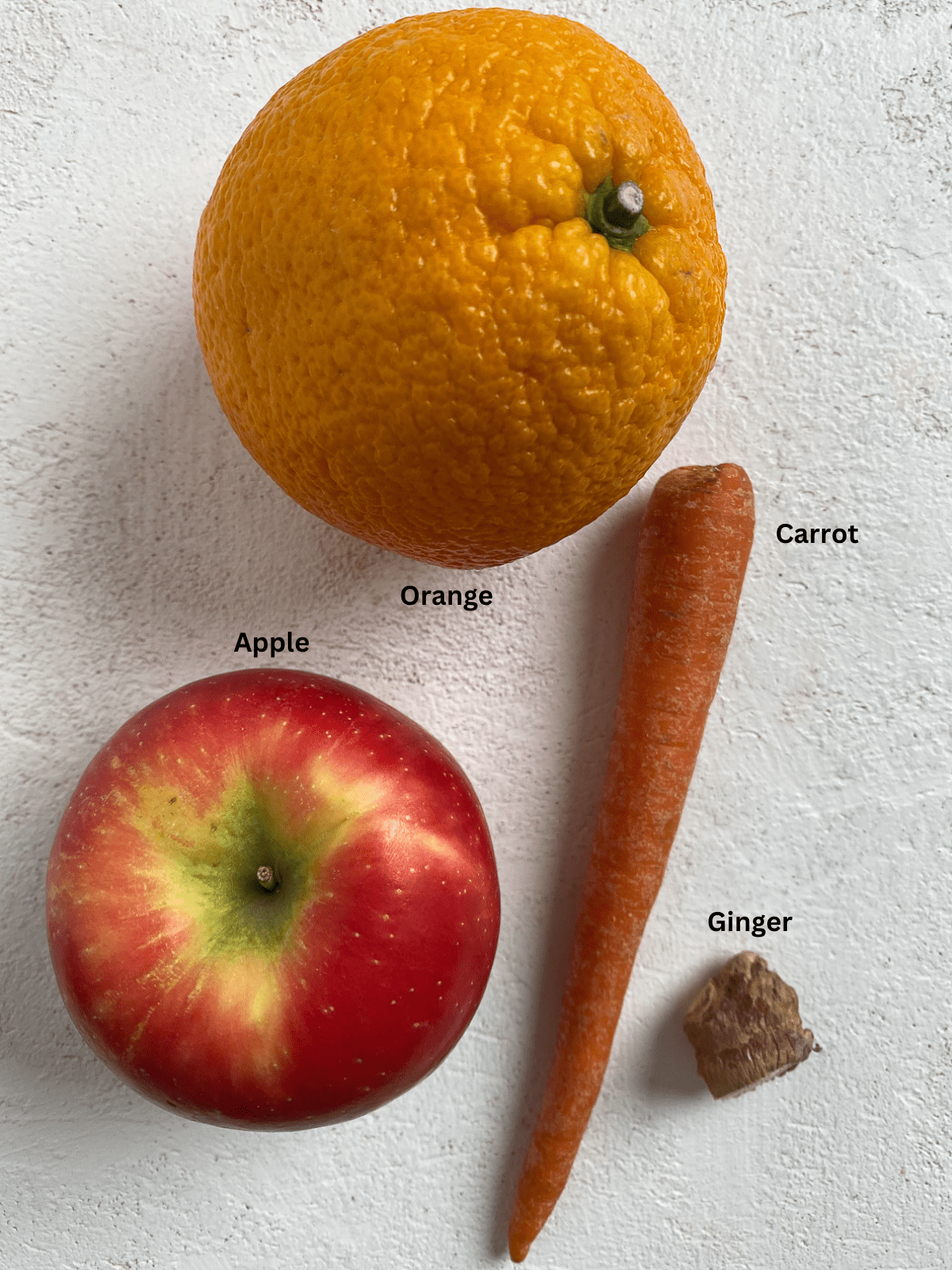 Ingredients for Apple OJ Carrot Juice measured out on a white surface.
