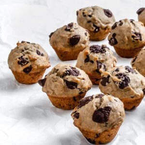 several completed Vegan Chocolate Chip Banana Muffins on a white surface