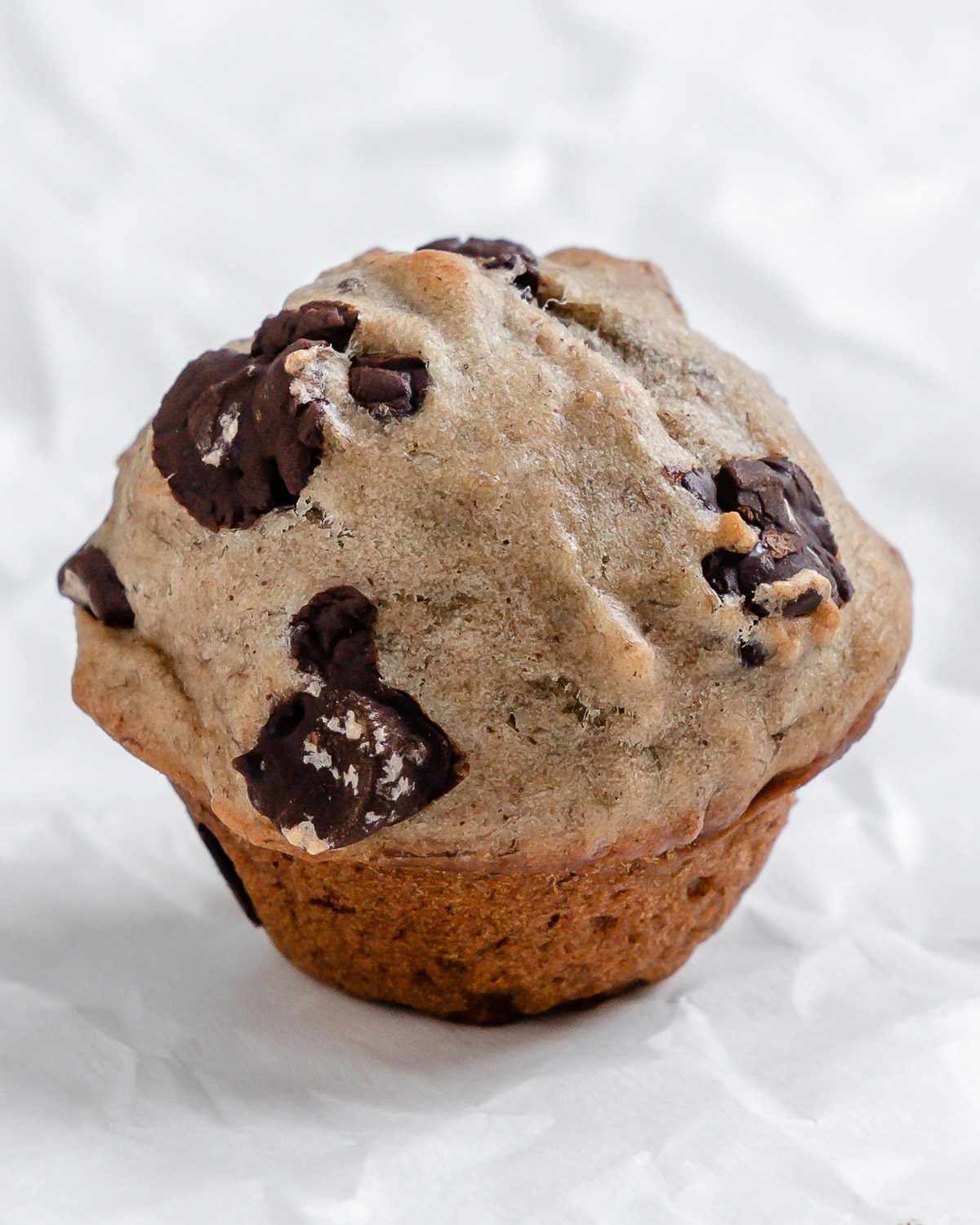 one completed Vegan Chocolate Chip Banana Muffin on a white surface