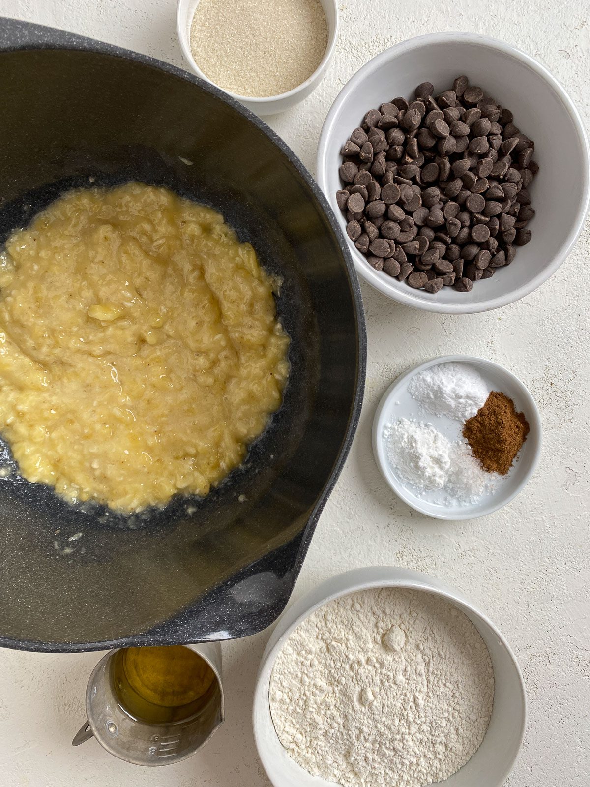 bowl of mashed bananas alongside ingredients for muffins