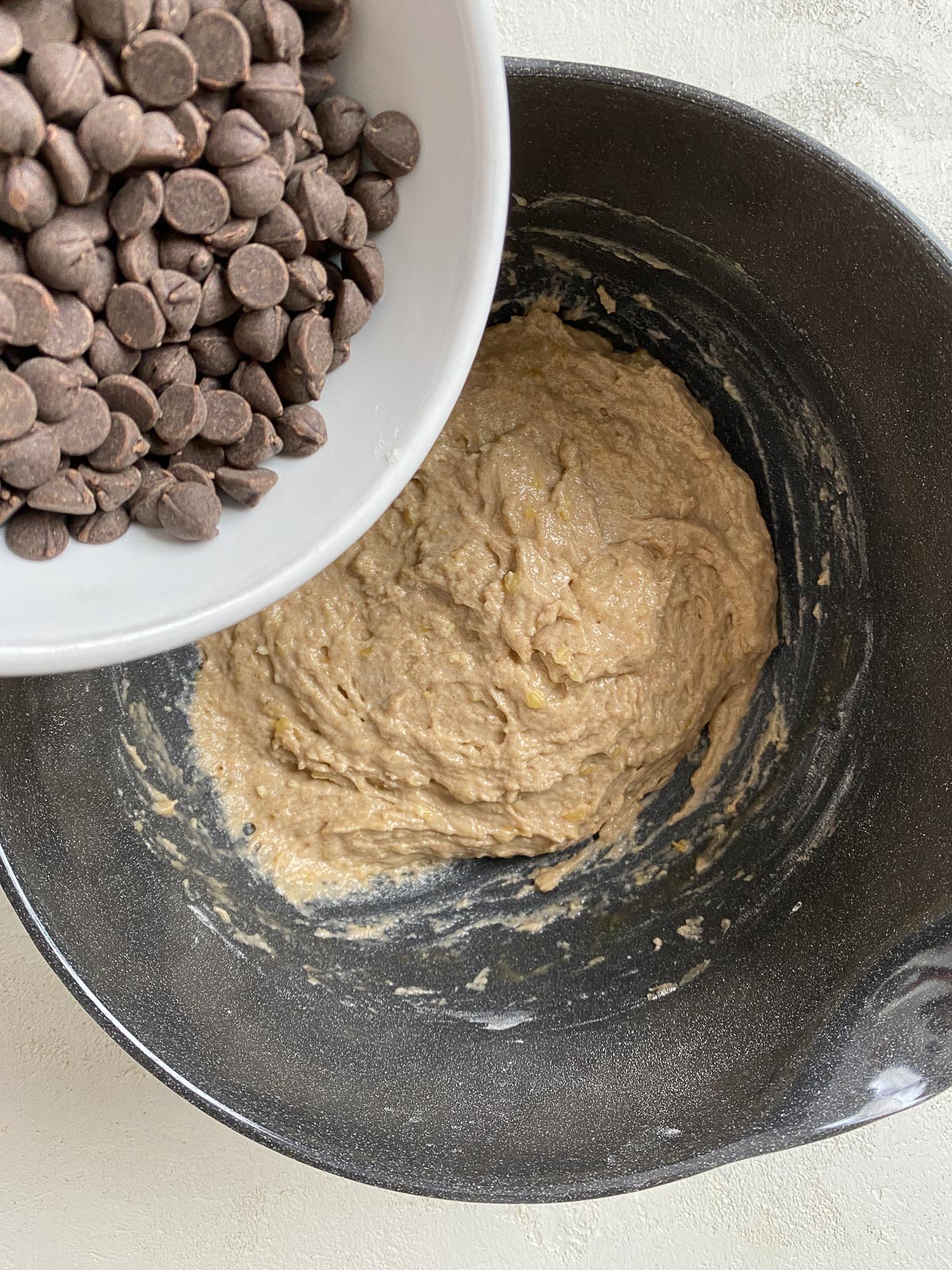 process shot showing addition of chocolate chips to muffin dough in bowl