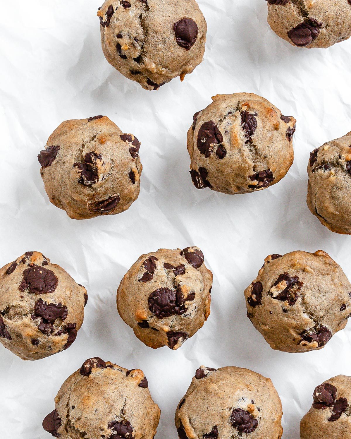 several completed Vegan Chocolate Chip Banana Muffins on a white surface