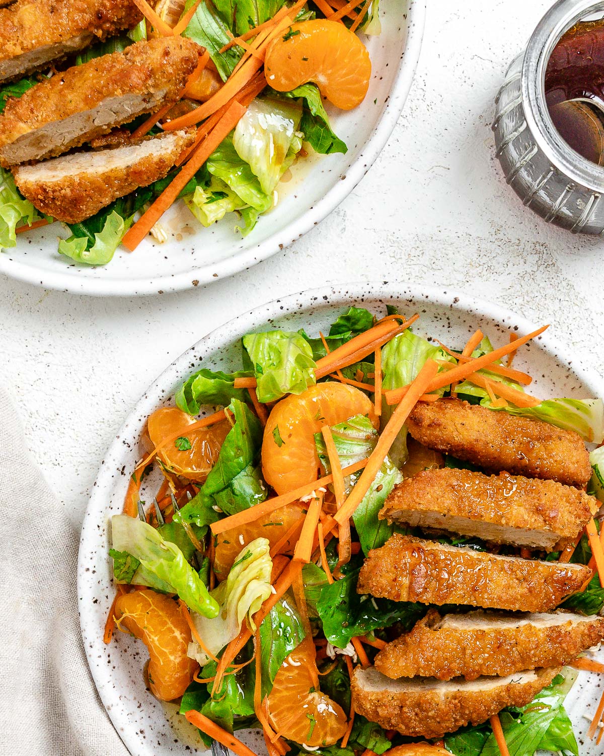 two completed Vegan Asian Mandarin Chicken Ramen Noodle Salad dishes on a white plate against a white background