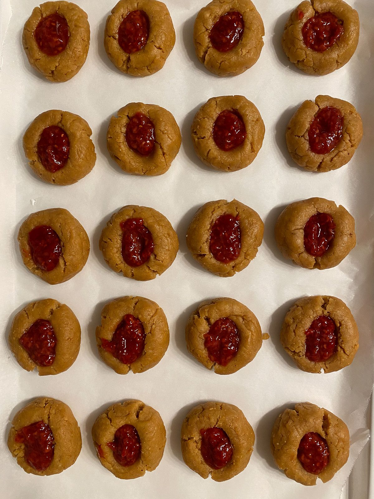 several pre-baked cookies lined up on a cookie sheet