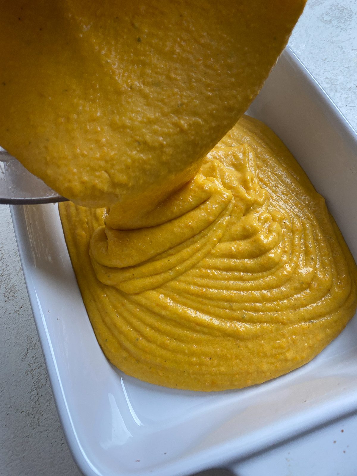 process shot showing vegan cheese being poured into baking dish