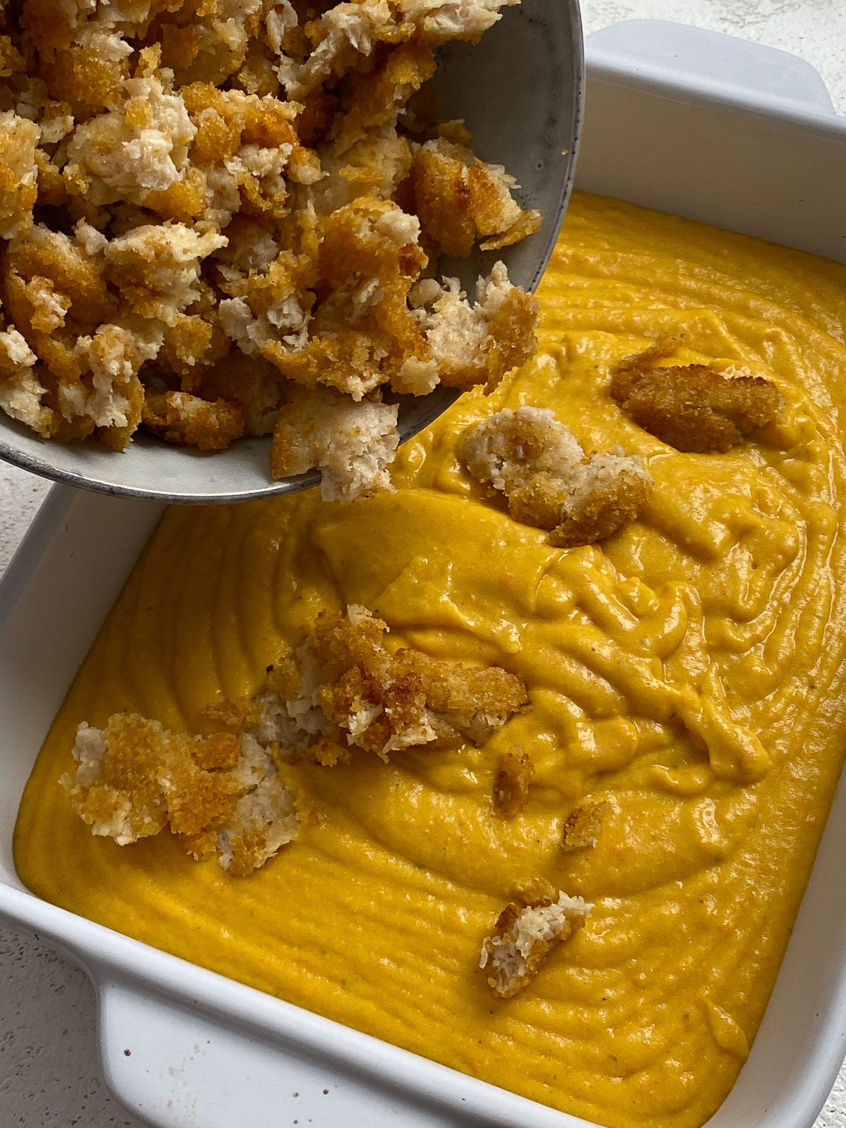 process shot showing vegan chicken being added to vegan cheese sauce