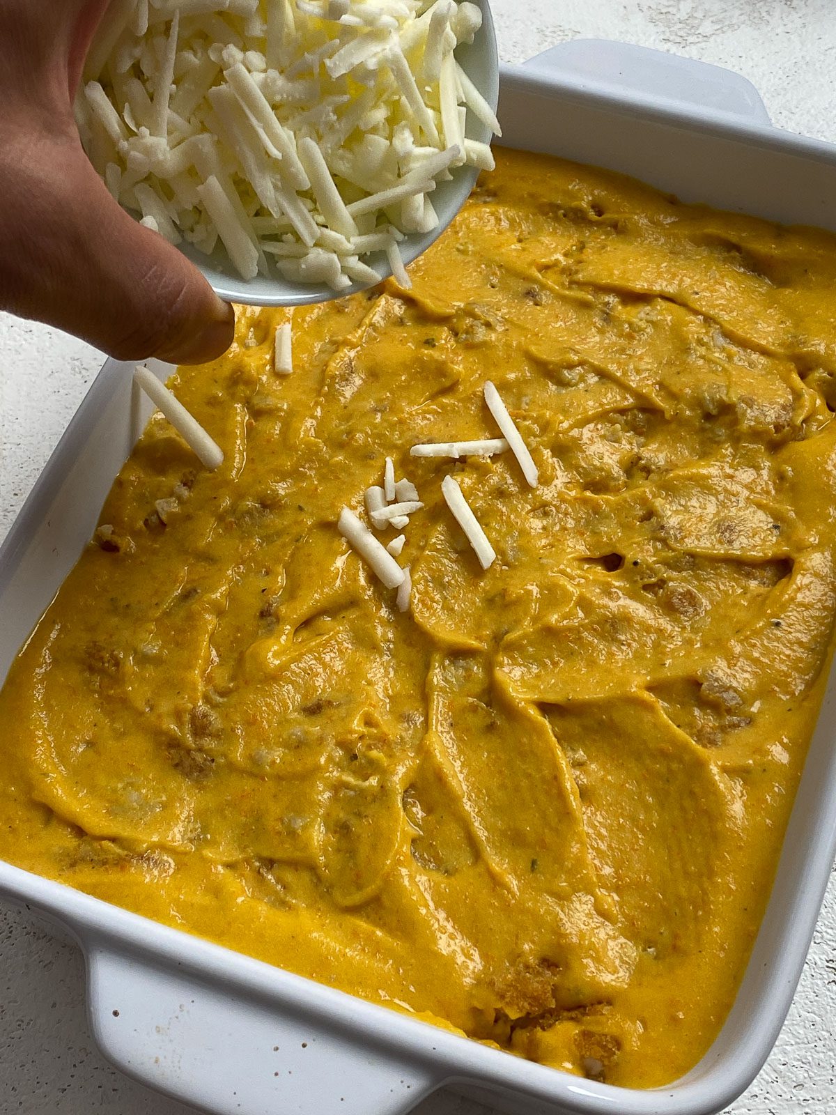 process shot showing vegan cheese shreds being added to baking tray