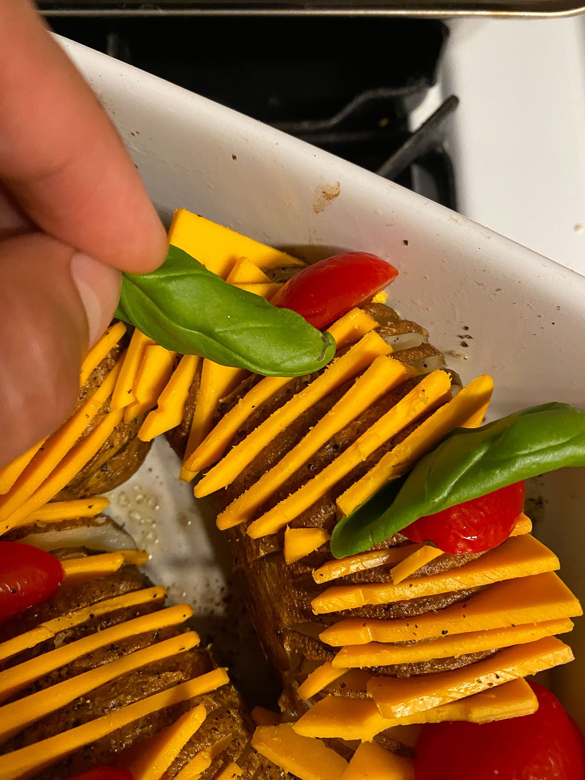 process of adding basil leaves to potatoes