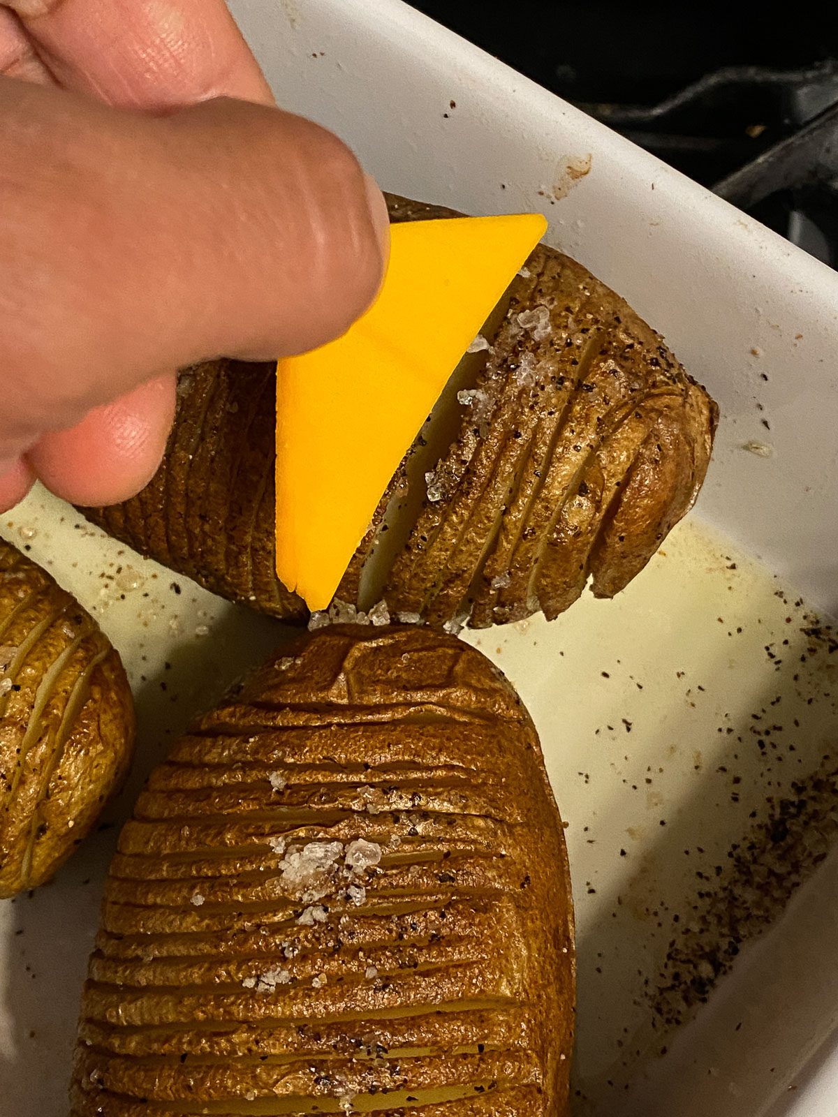 process of adding triangular cheese slices to potatoes