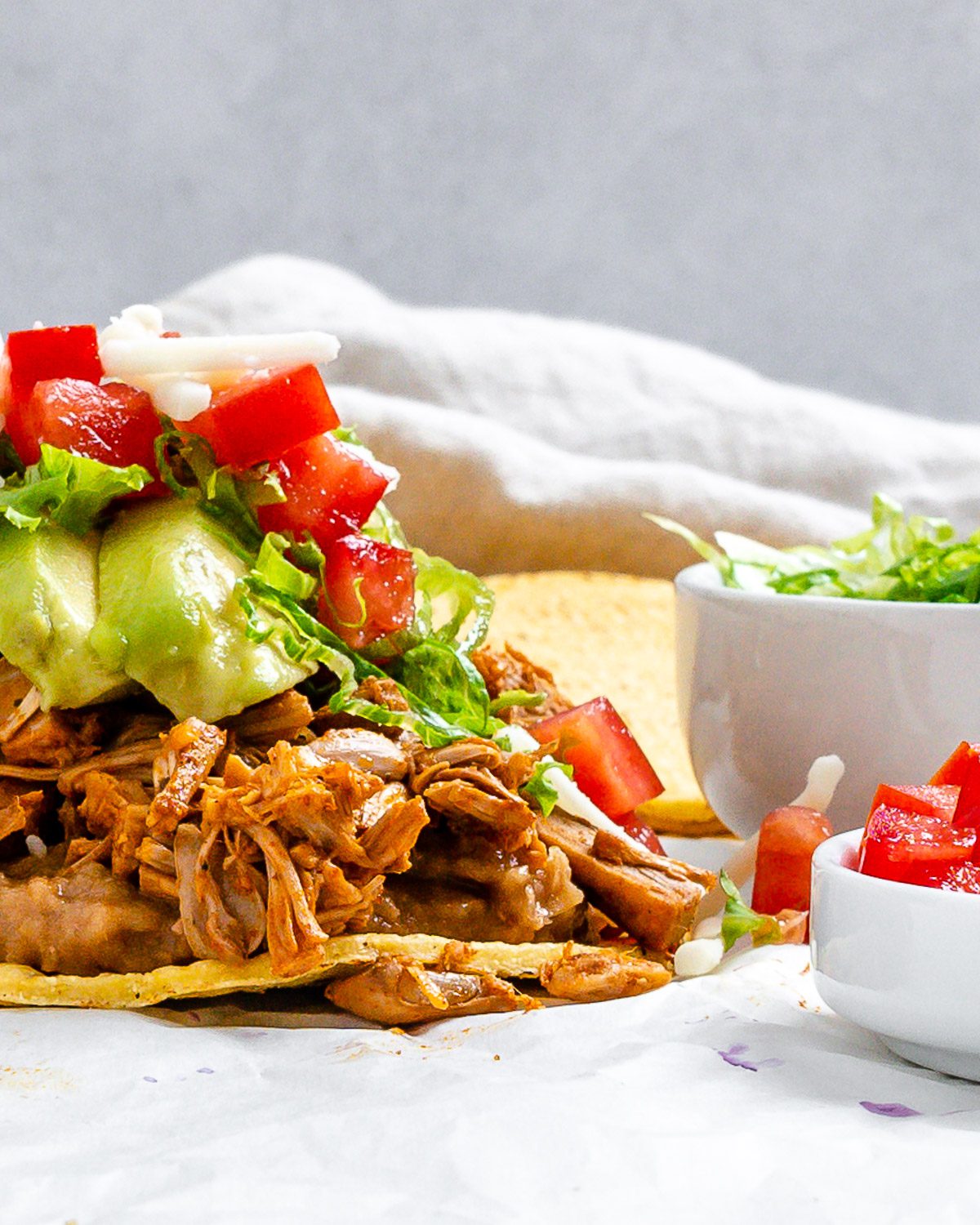 completed Vegan Jackfruit Tostadas on a white surface with veggies on the side