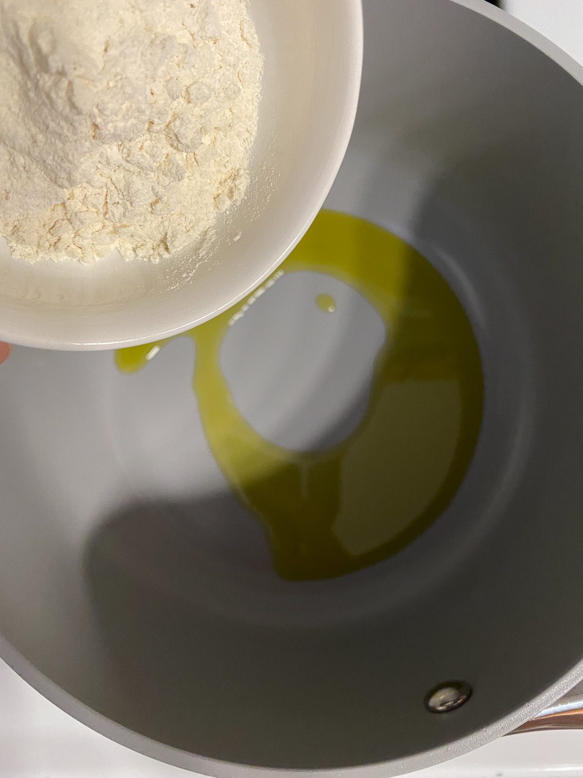 process of flour being added to pan with oil