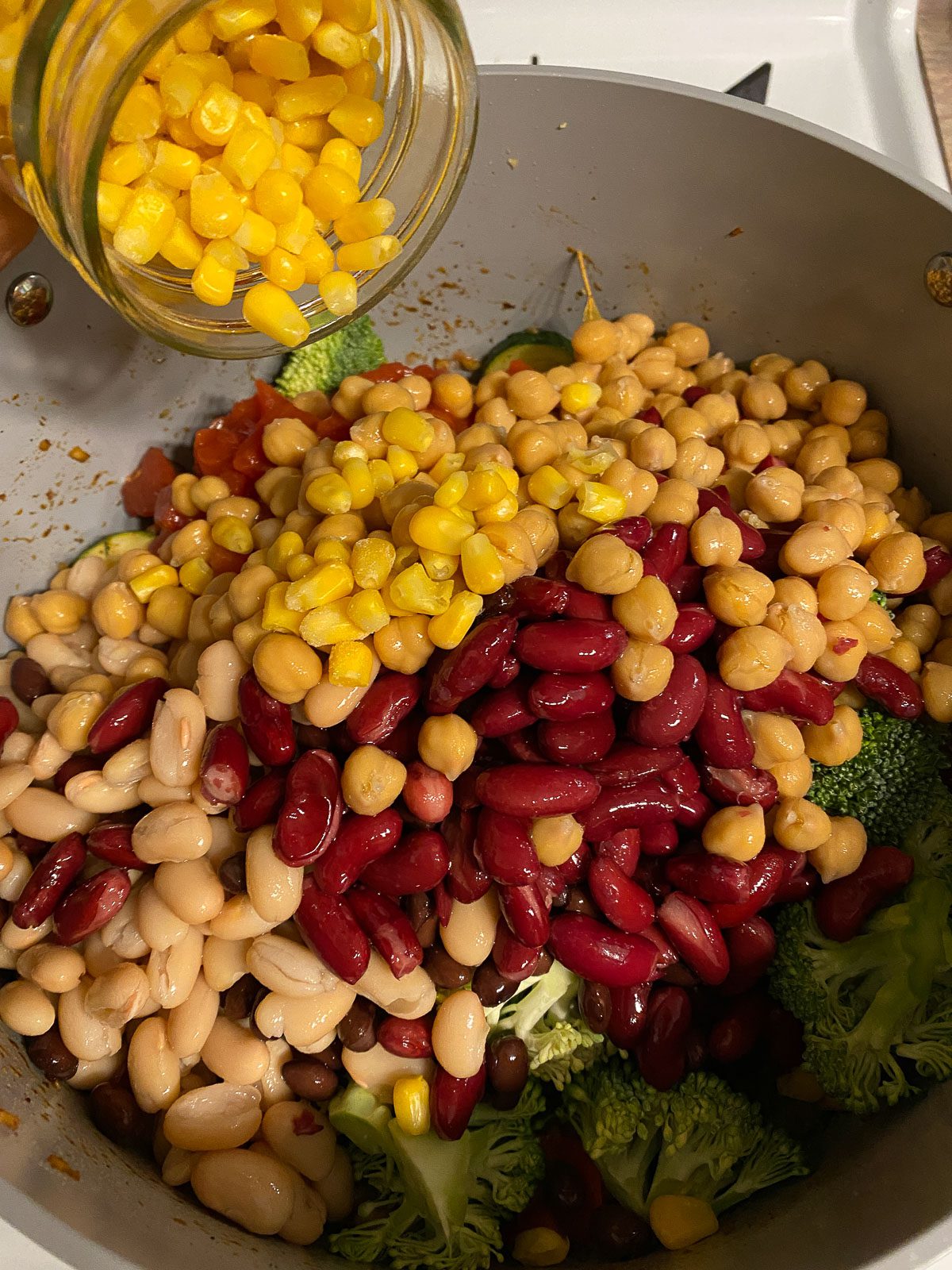 process of adding corn to mixed pan of veggies