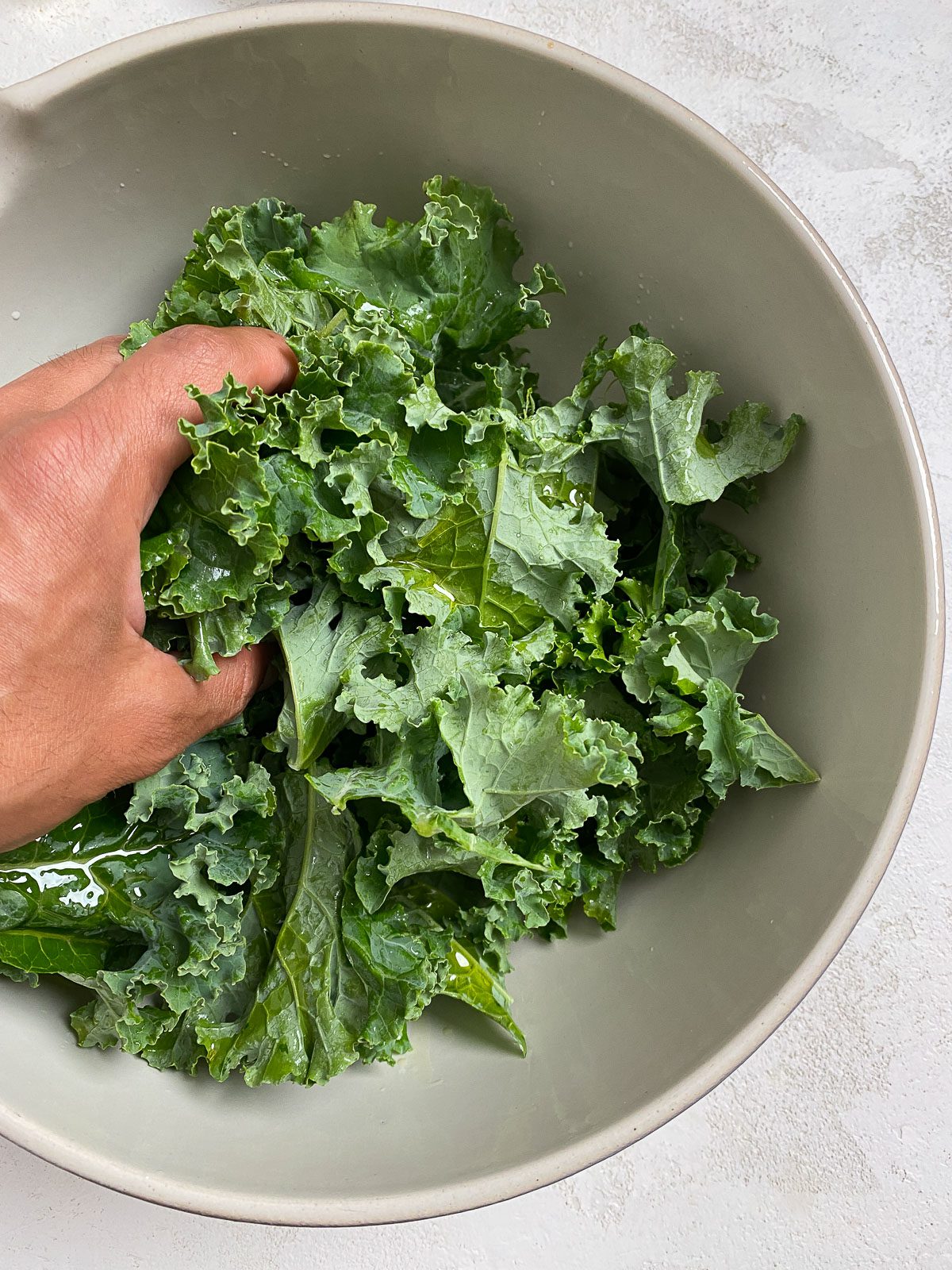 process shot showing massaging kale in white bowl