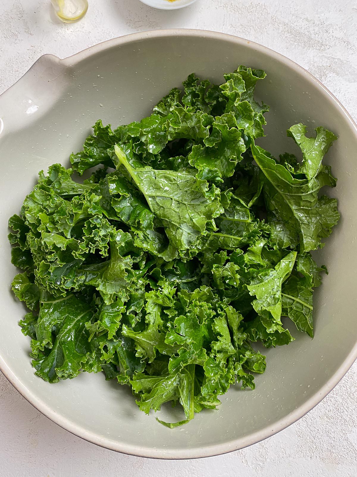 post shot of massaging kale in white bowl