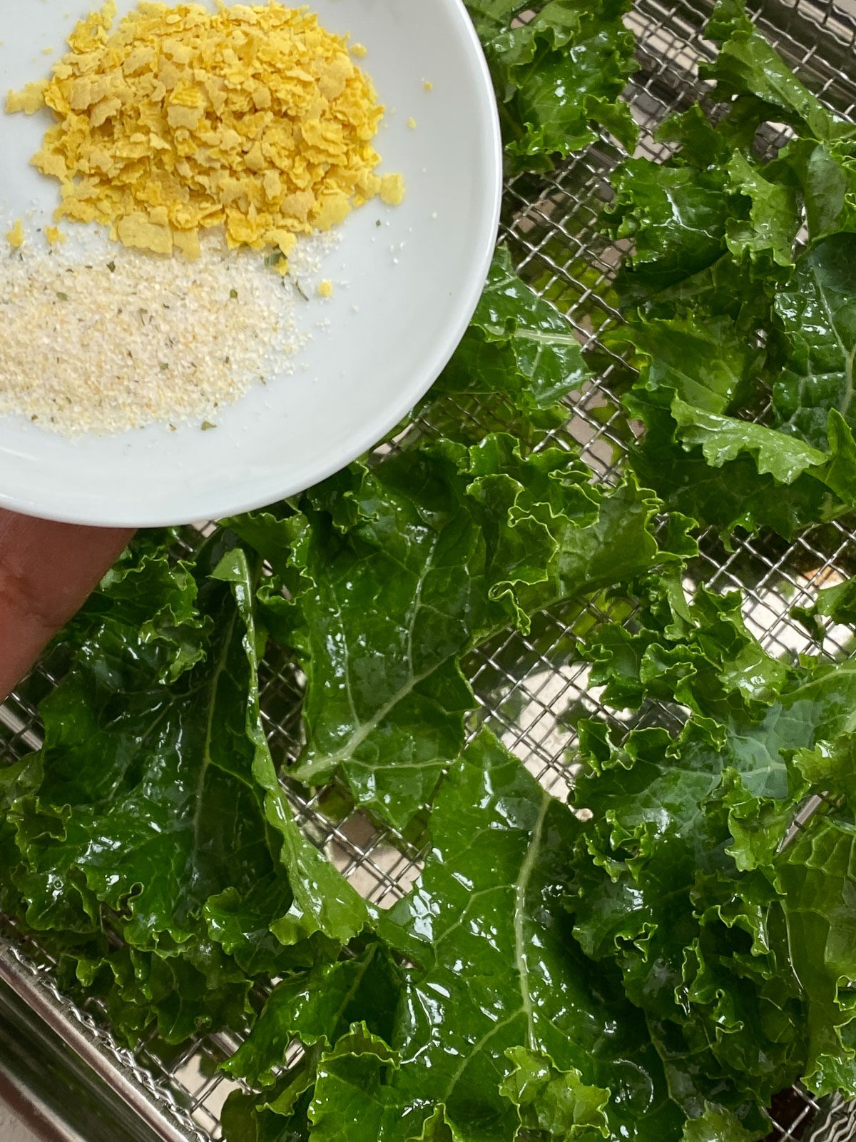 process of adding seasonings to kale on rack