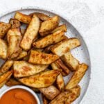 completed Air Fryer Potato Wedges plated on a white plate alongside a sauce
