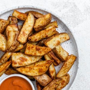 completed Air Fryer Potato Wedges plated on a white plate alongside a sauce