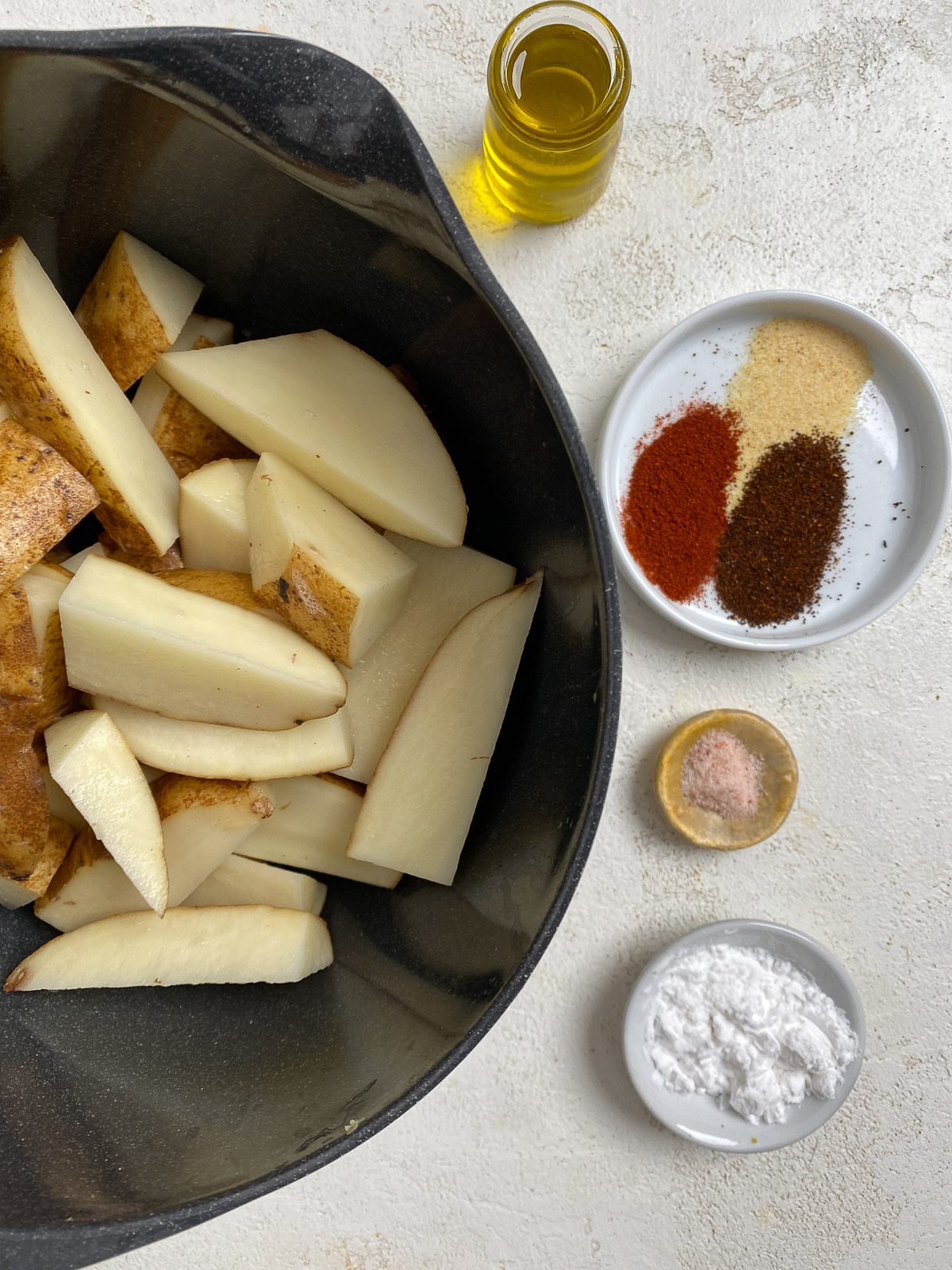 raw potatoes alongside spices for air fryer potato wedges