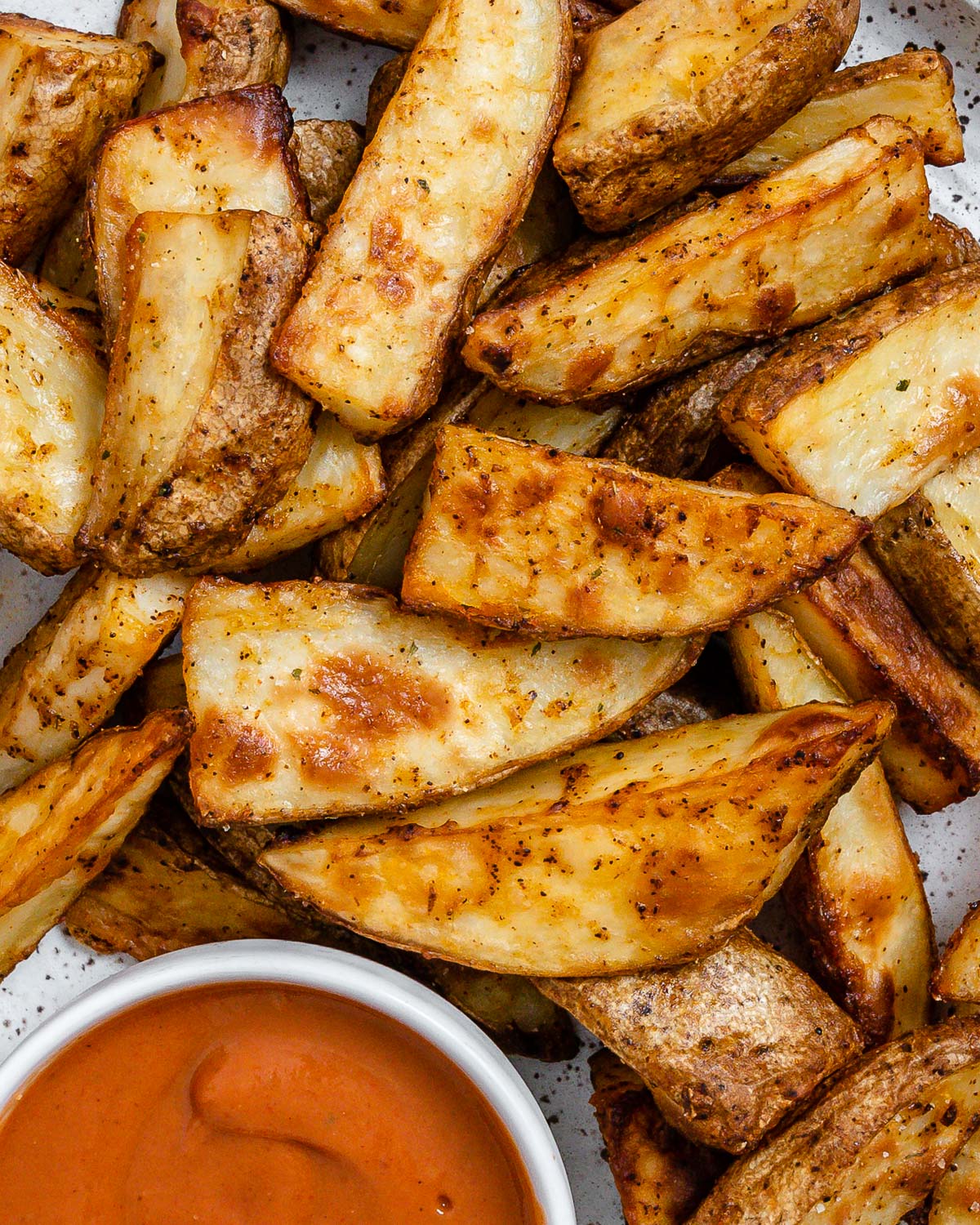 completed Air Fryer Potato Wedges plated on a white plate alongside a sauce