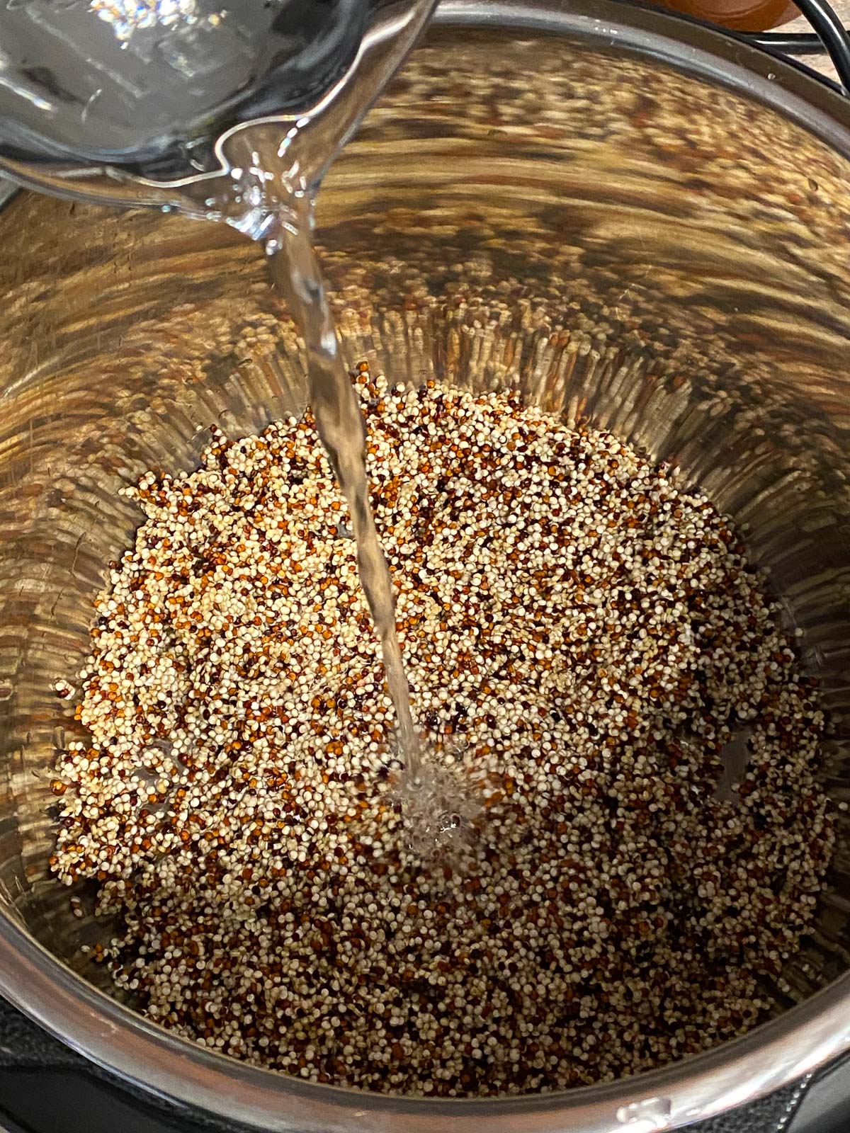 process shot of water being poured into bowl of quinoa